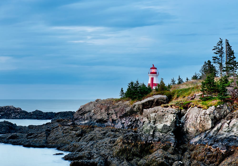 An image rendering of rocks and a light house by the ocean.