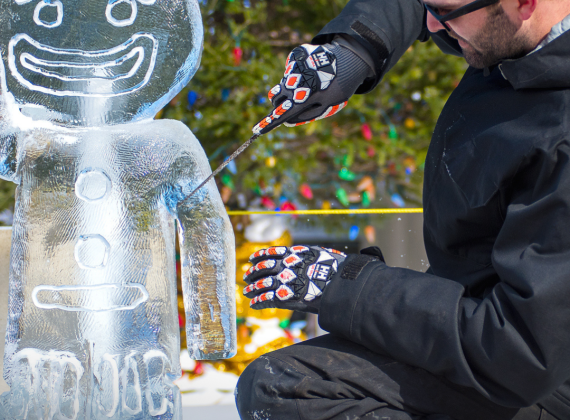 Man carving an ice statue into a gingerbread man 