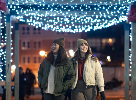 Two women walking under canopy with winter themed lights 