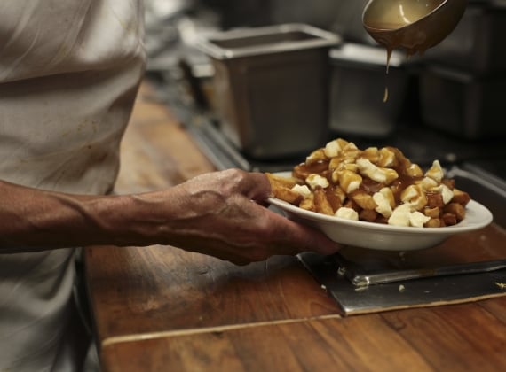 Gravy being poured on poutine