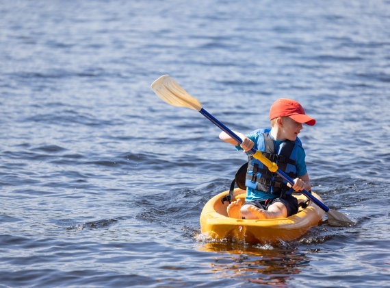 Young boy kayaking on a lake during summer vacations - stock photo