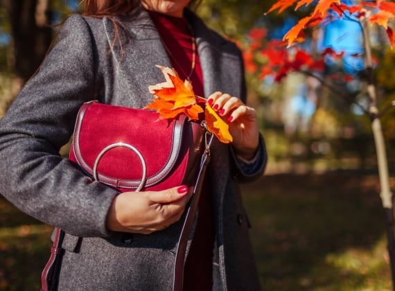 Woman in fall attire holding Purse 