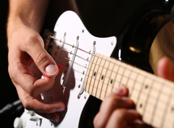 A hand picking and electric guitar