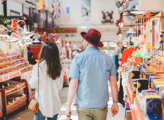 A couple walking in a sunny market.