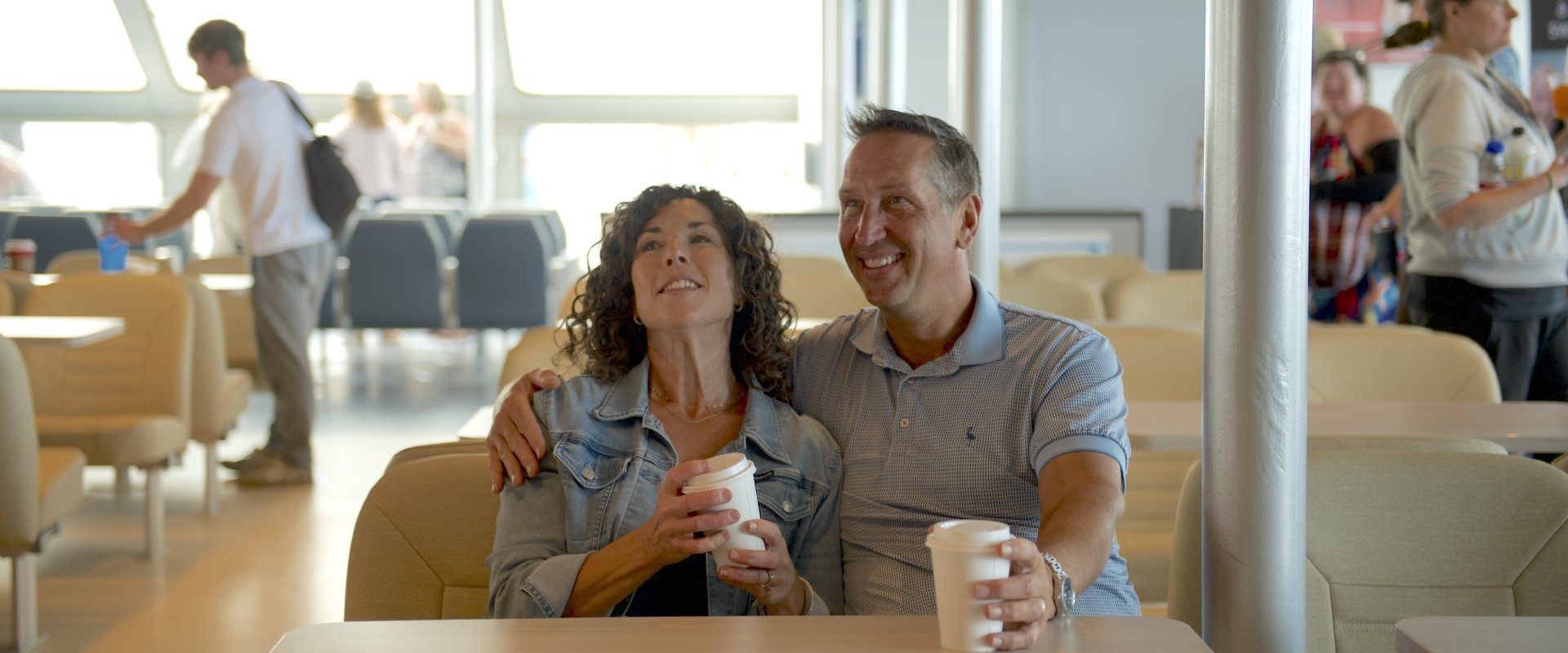 Man and woman having a coffee on board an NFL ferry 